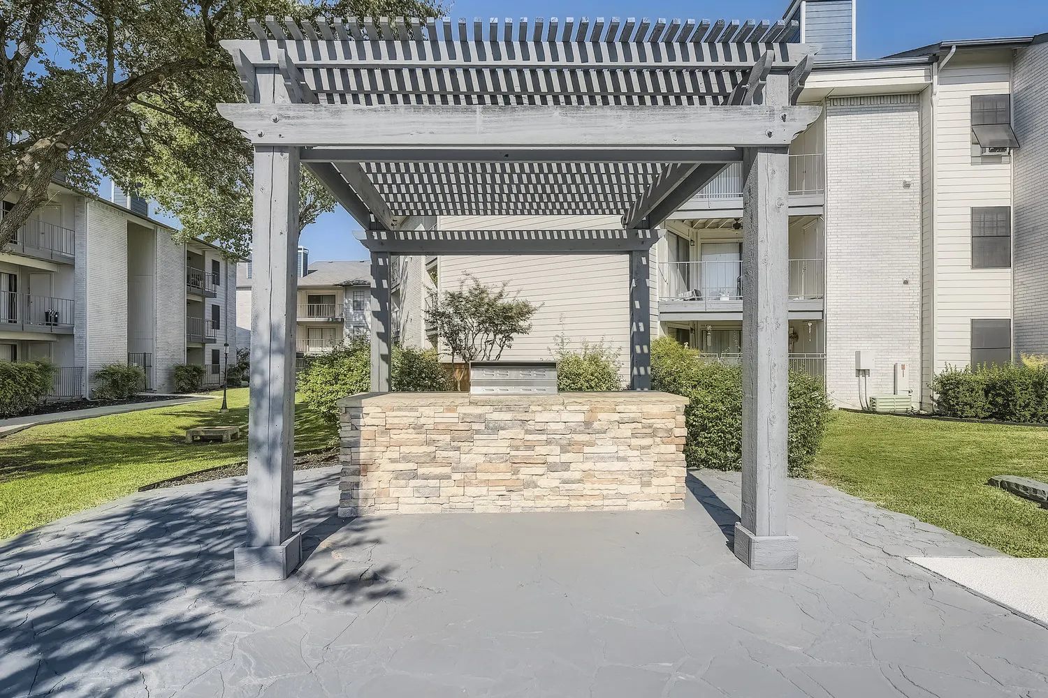 Outdoor BBQ grill station with stone counter under a pergola