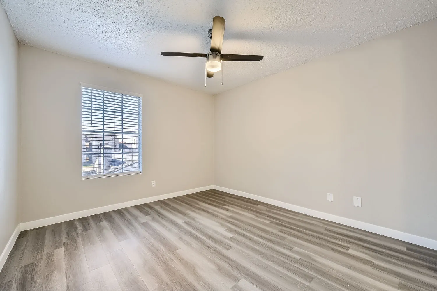 Primary bedroom, wood-style plank flooring, ceiling fan, window