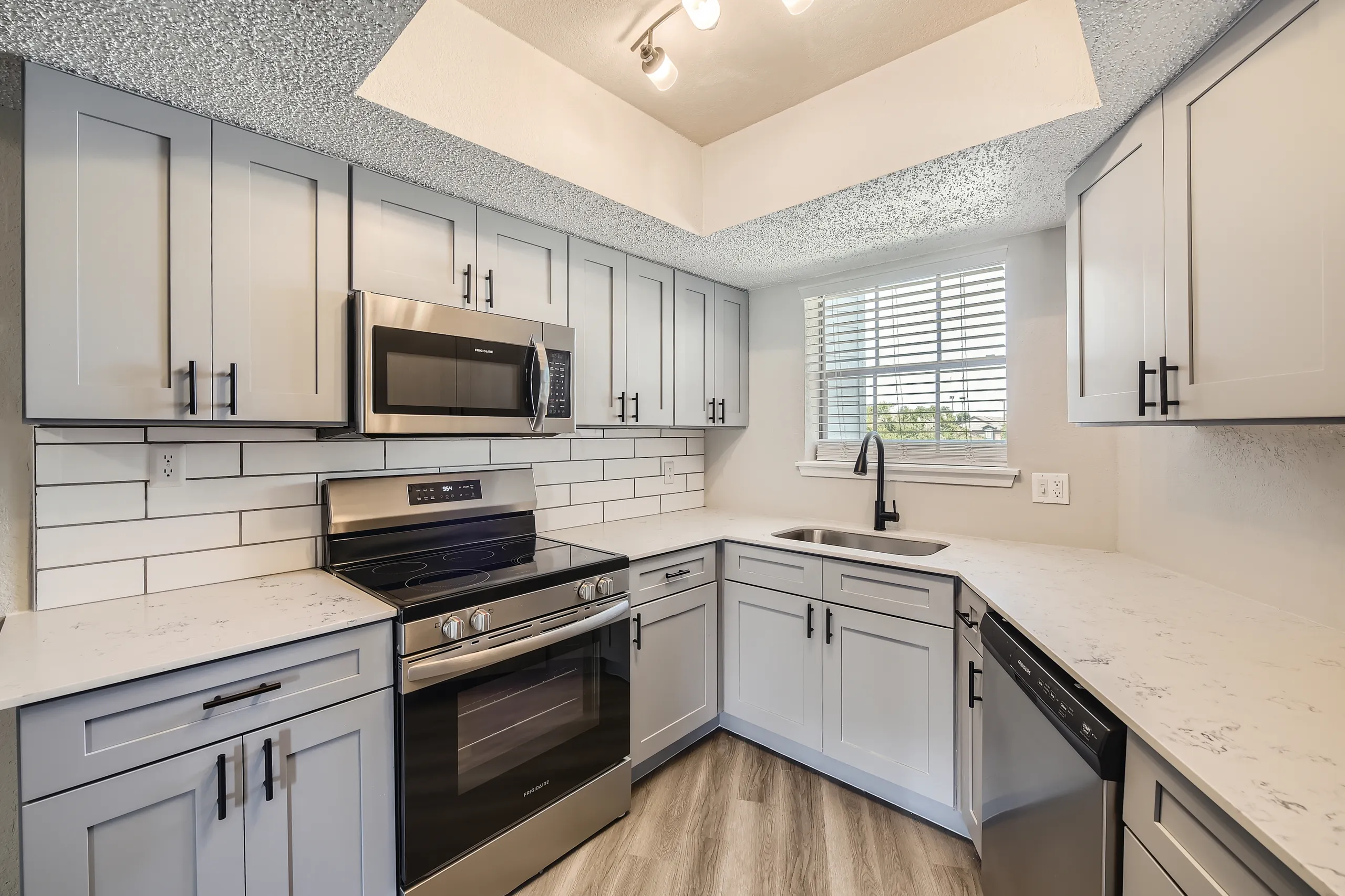 Kitchen with gray shaker cabinets, quartz countertops, subway tile backsplash, stainless steel appliances