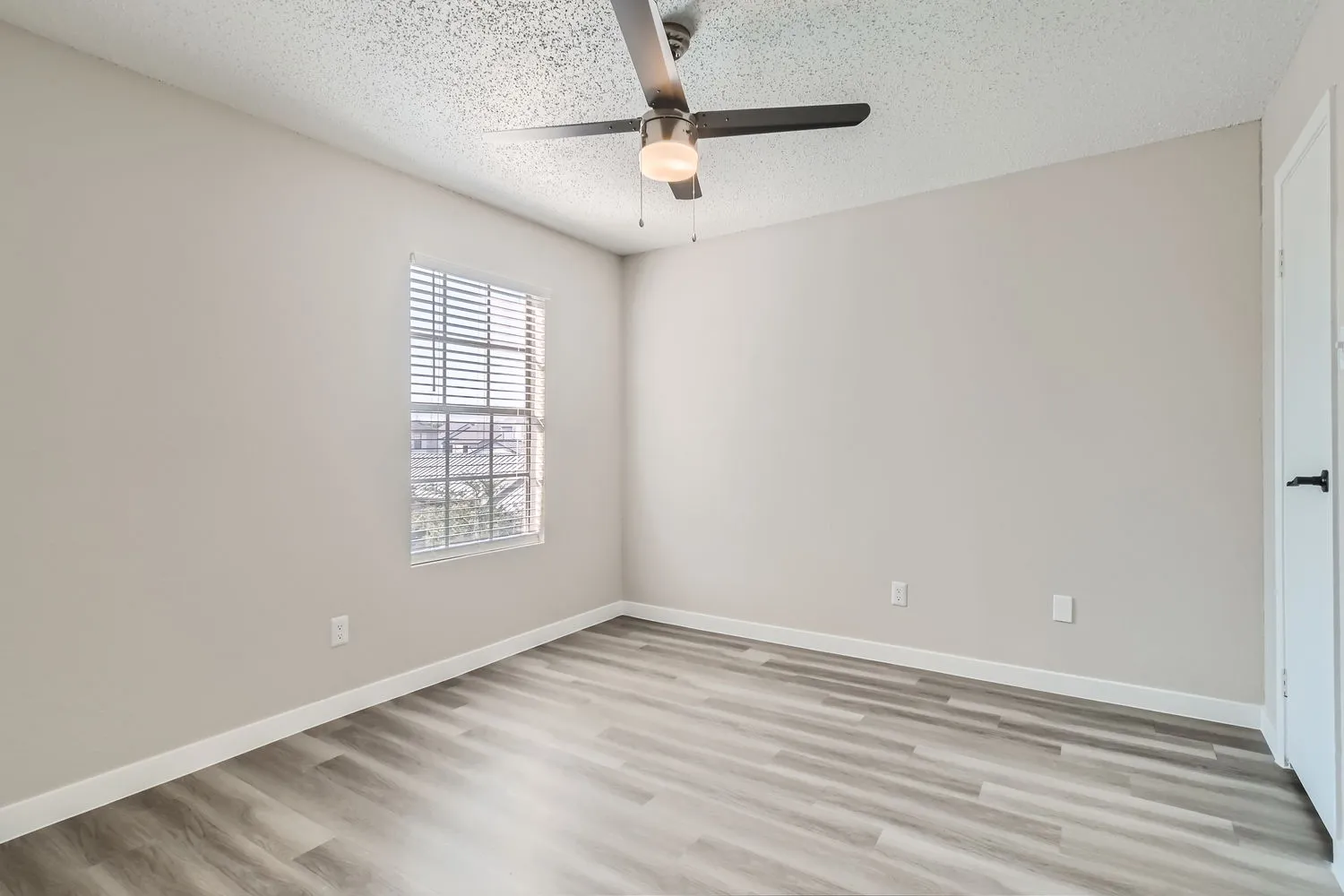 Primary bedroom, wood-style plank flooring, ceiling fan, window
