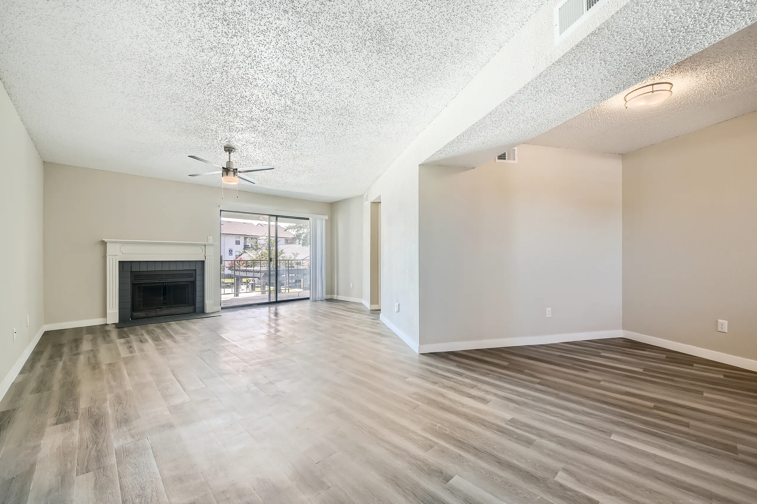 A6 Platinum floor plan, open living room with wood-style plank flooring, ceiling fan, fireplace, sliding glass door to balcony