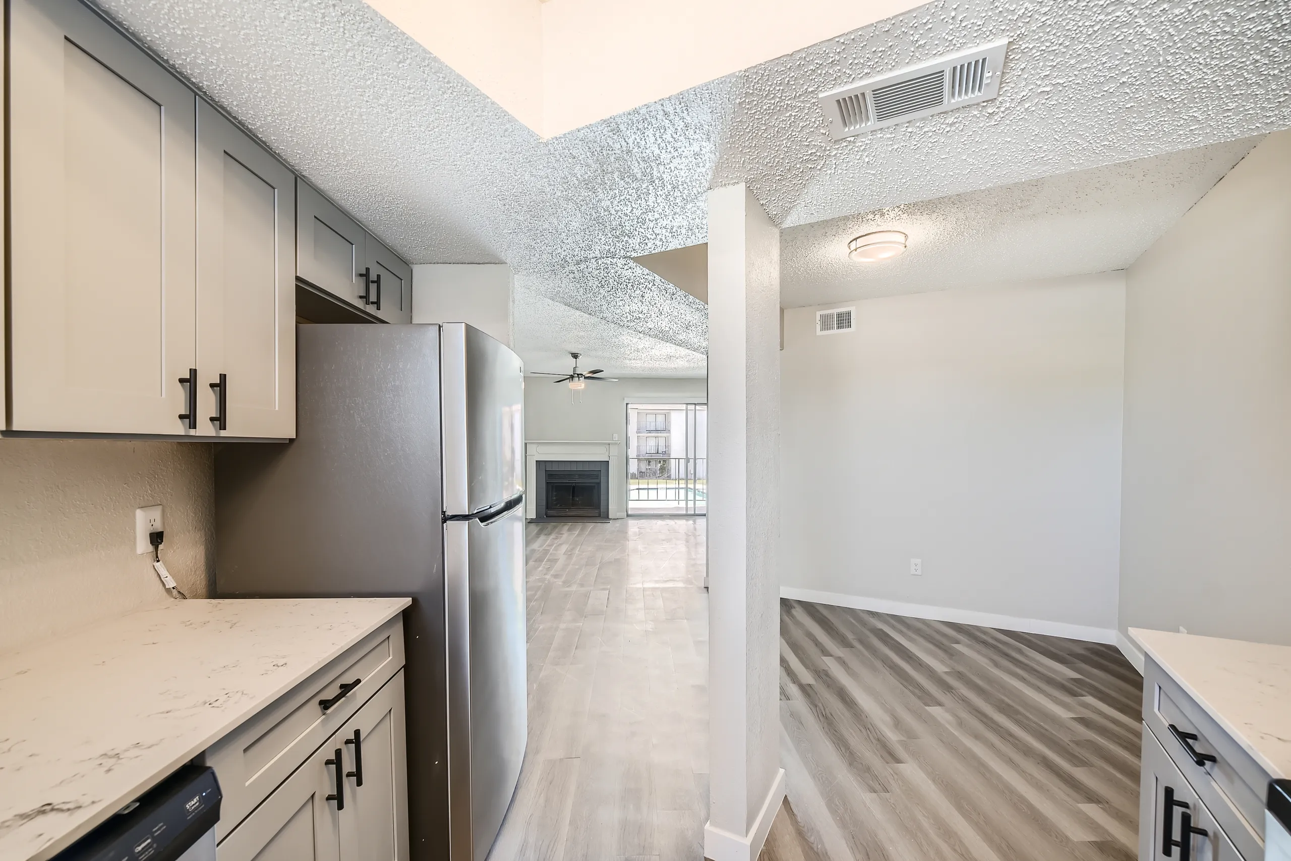 Kitchen with stainless steel refrigerator, quartz countertops, open view to living room and dining area