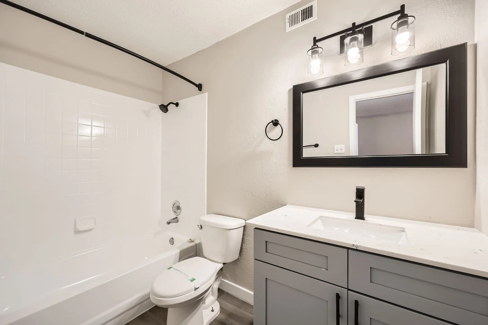 Primary bathroom with quartz vanity countertop, matte black fixtures, framed mirror, tub-shower combo