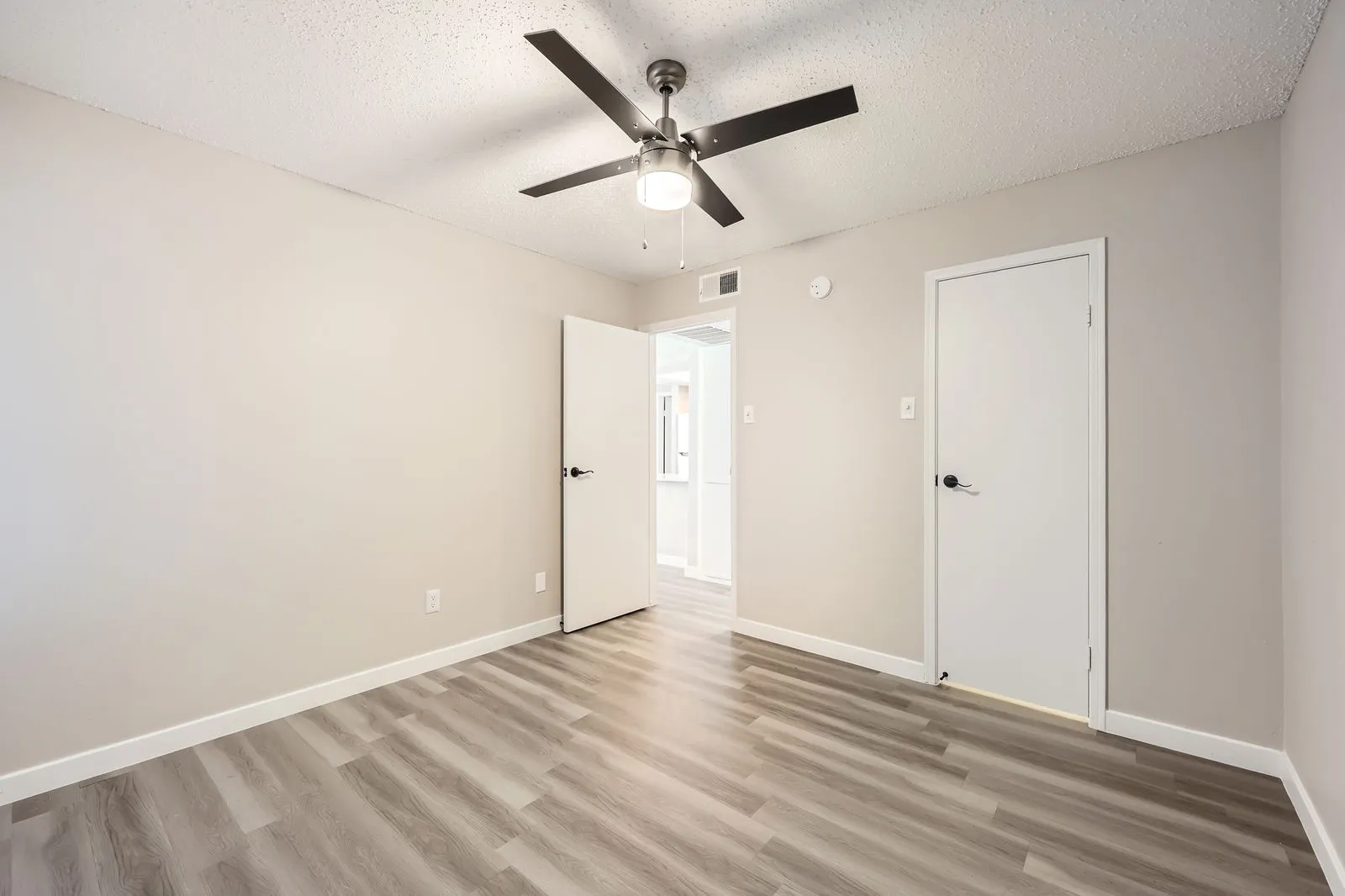 Bedroom with wood-style plank flooring, ceiling fan, closet door
