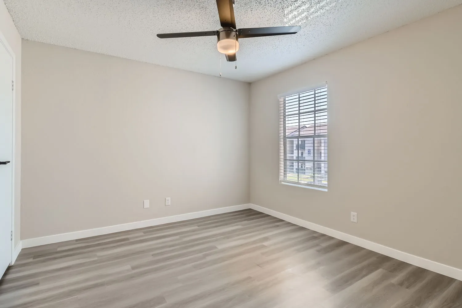 Primary bedroom, wood-style plank flooring, ceiling fan, window
