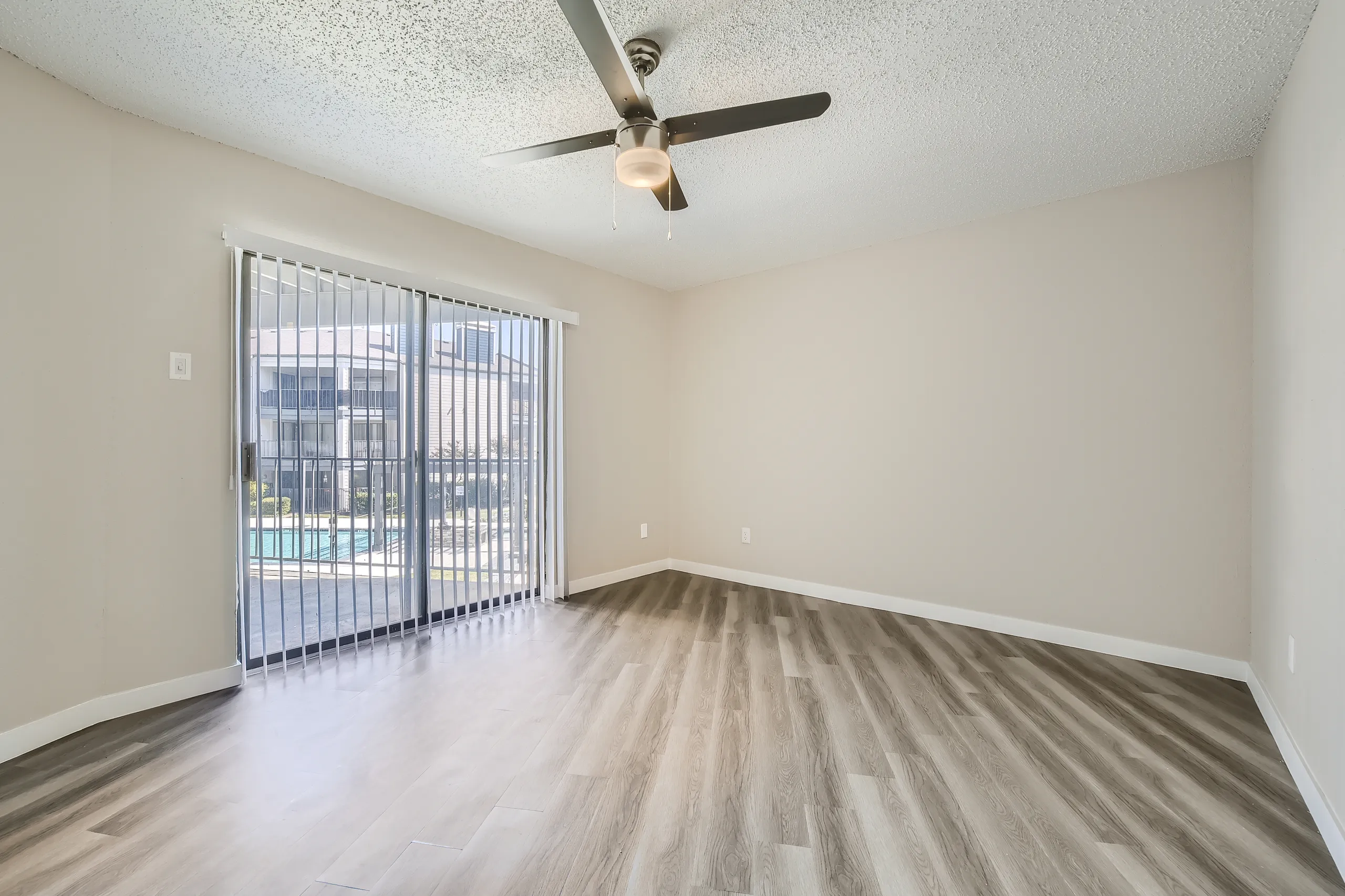 Primary bedroom with wood-style plank flooring, ceiling fan, sliding glass door to balcony, pool view