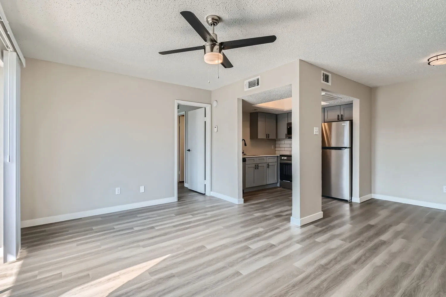 A2 Platinum living room, wood-style plank flooring, ceiling fan, open to kitchen