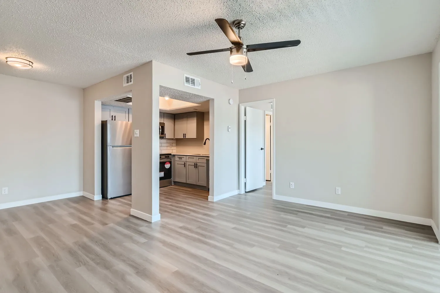 A3 Platinum living room, wood-style plank flooring, ceiling fan, open to kitchen