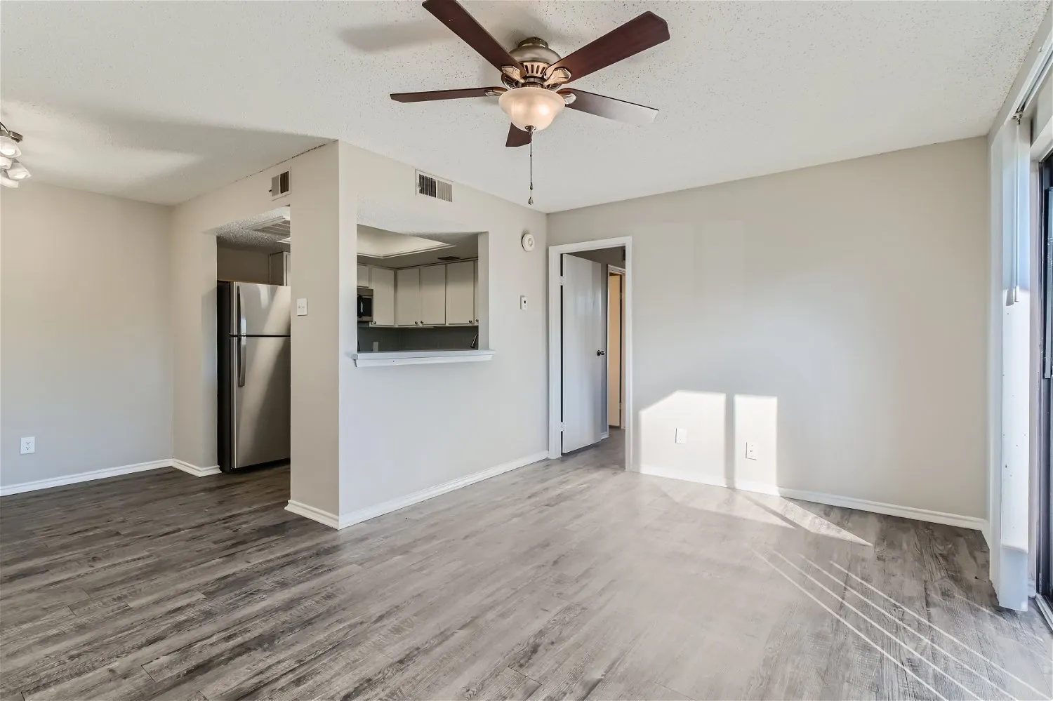 A2 Classic living room, wood-style plank flooring, ceiling fan, open to kitchen