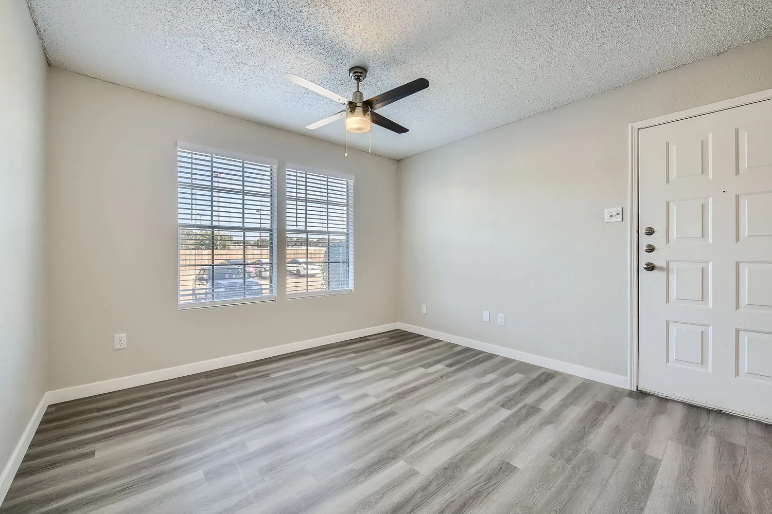 A1 Platinum living room, wood-style plank flooring, ceiling fan, entry door