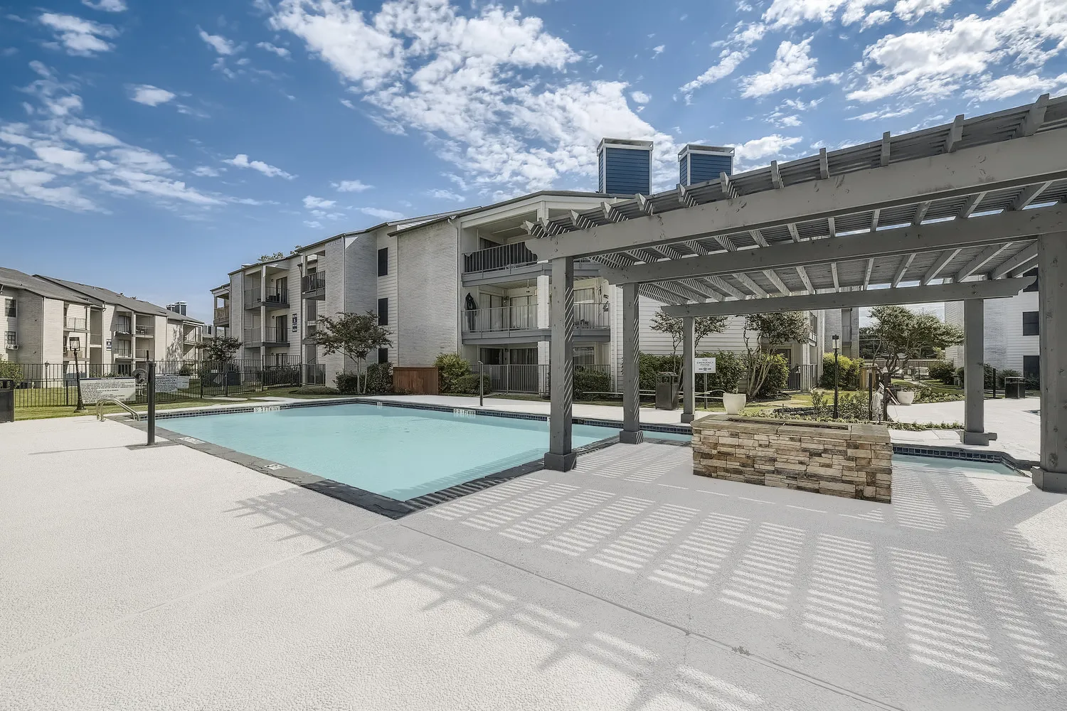 Community pool with pergola and stone-accented fire feature