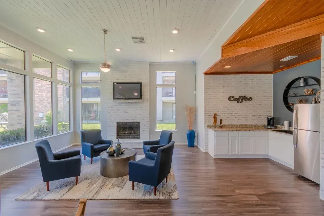Resident lounge with fireplace, wall-mounted TV, coffee bar with granite countertop, wood-style plank flooring