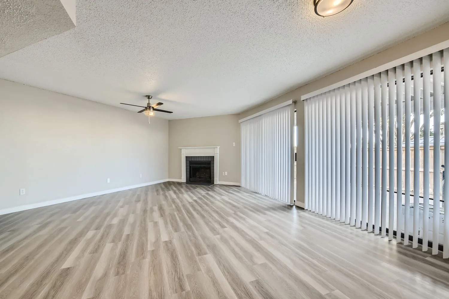 B3 Platinum floor plan, open living room with wood-style plank flooring, ceiling fan, fireplace, sliding glass door to patio