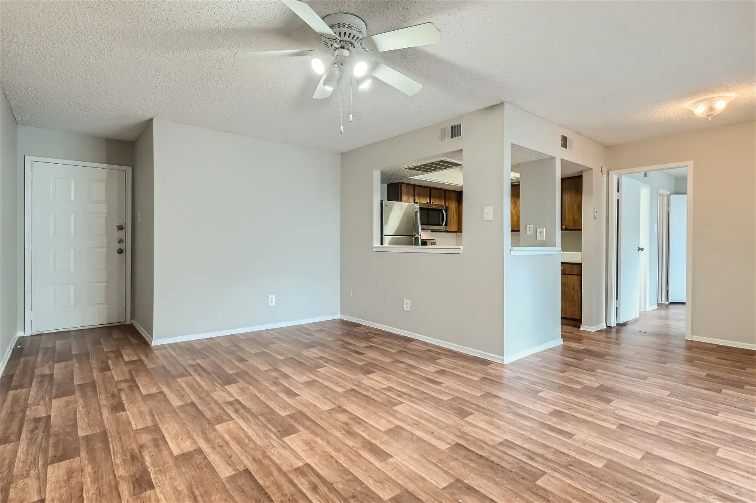 Living room, ceiling fan, entry door, open to kitchen