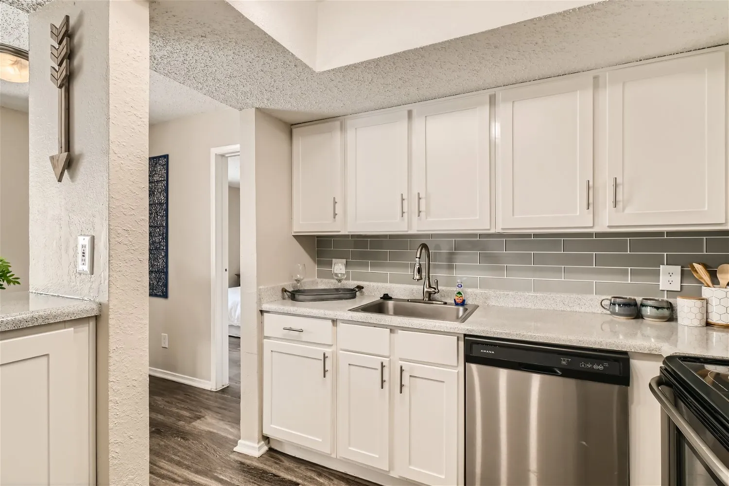 Kitchen counter with dishwasher and sink, quartz countertop, white cabinetry