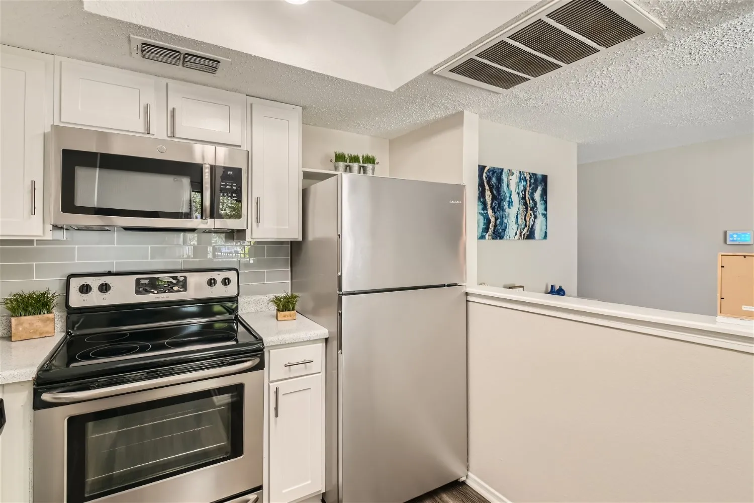 Kitchen, stainless steel appliances, white cabinetry, tile backsplash