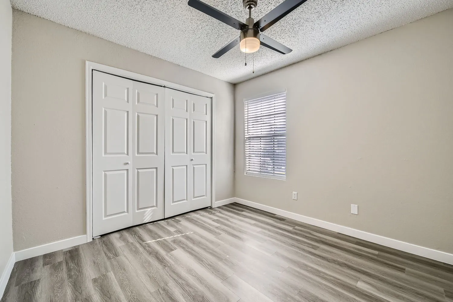 Bedroom with wood-style plank flooring, ceiling fan, double closet doors, window with natural light