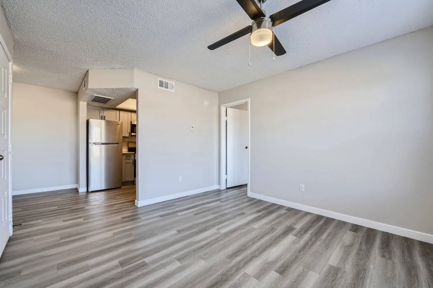 Living room, ceiling fan, wood-style plank flooring, open to kitchen