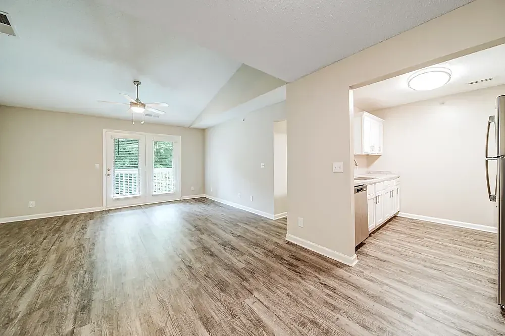 Open concept living and kitchen area, wood-style plank flooring, ceiling fan, sliding glass doors with deck view