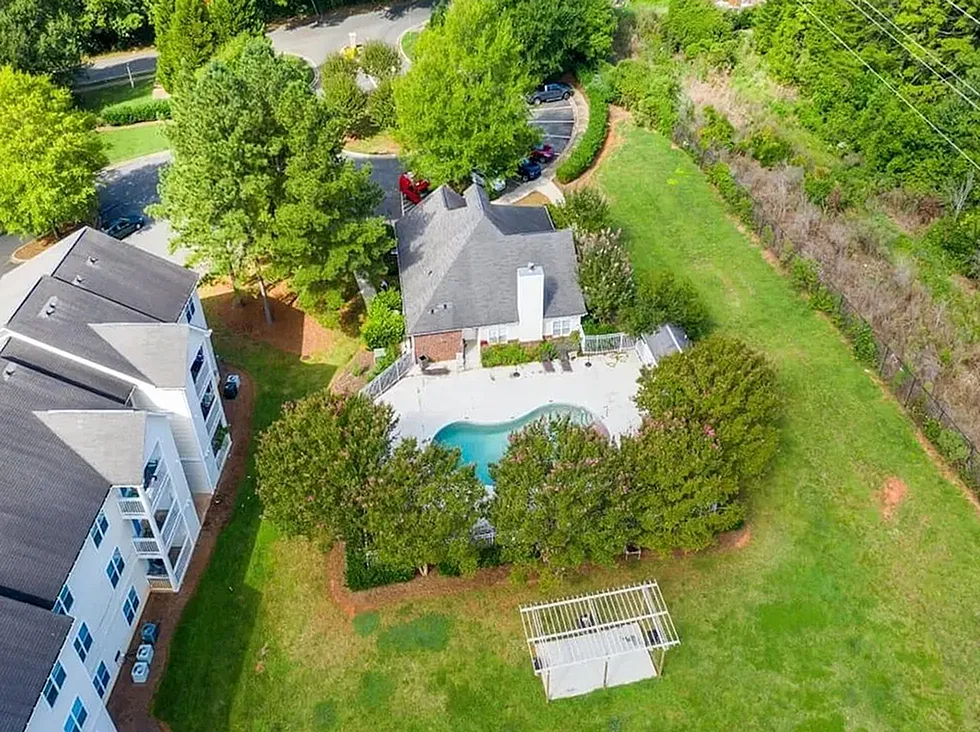 Aerial view of home with pool, manicured lawn, mature trees, surrounding greenery