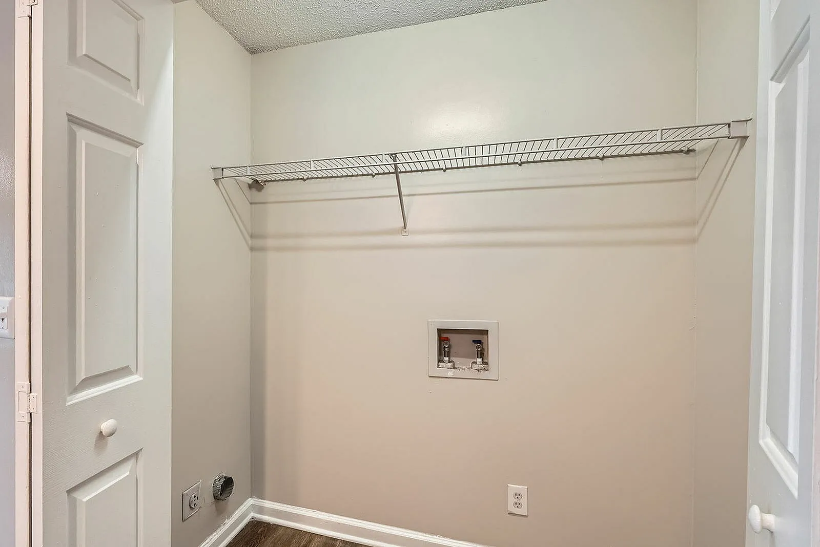 Walk-in closet, metal wire shelving, wood-style plank flooring, built-in storage nook, white walls