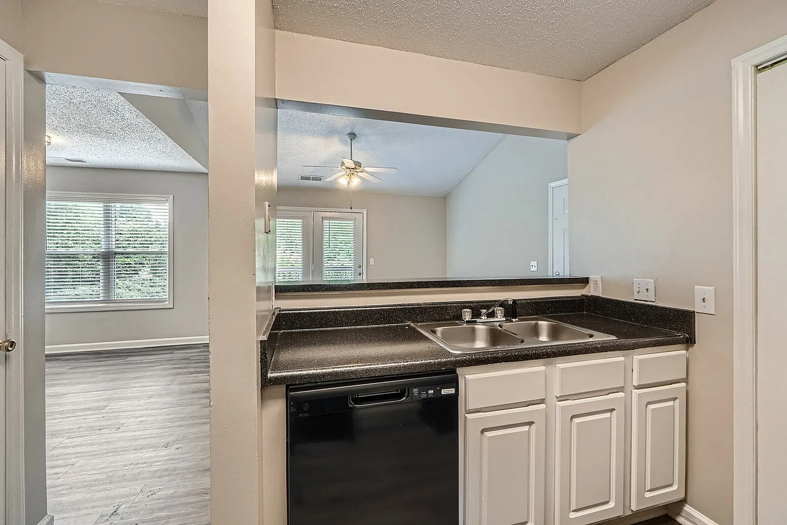 Kitchen, cream cabinetry, black speckled countertops, stainless sink, black dishwasher