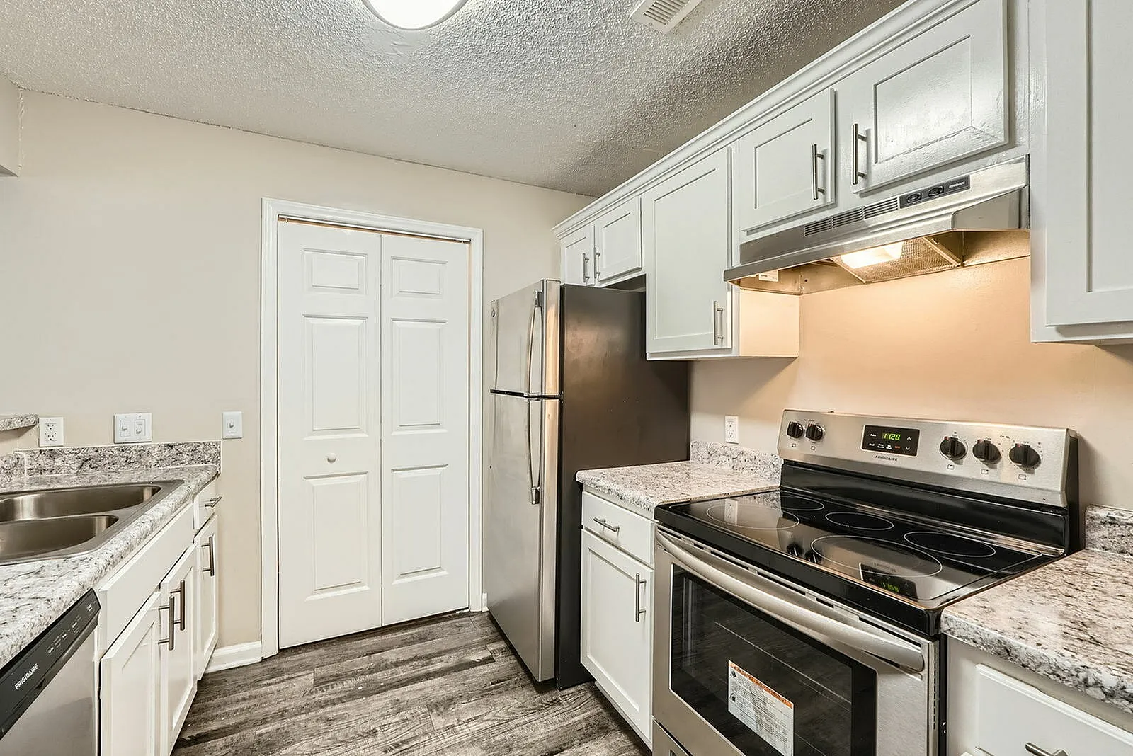 Kitchen, white shaker cabinetry, granite countertops, stainless appliances, wood-style plank flooring