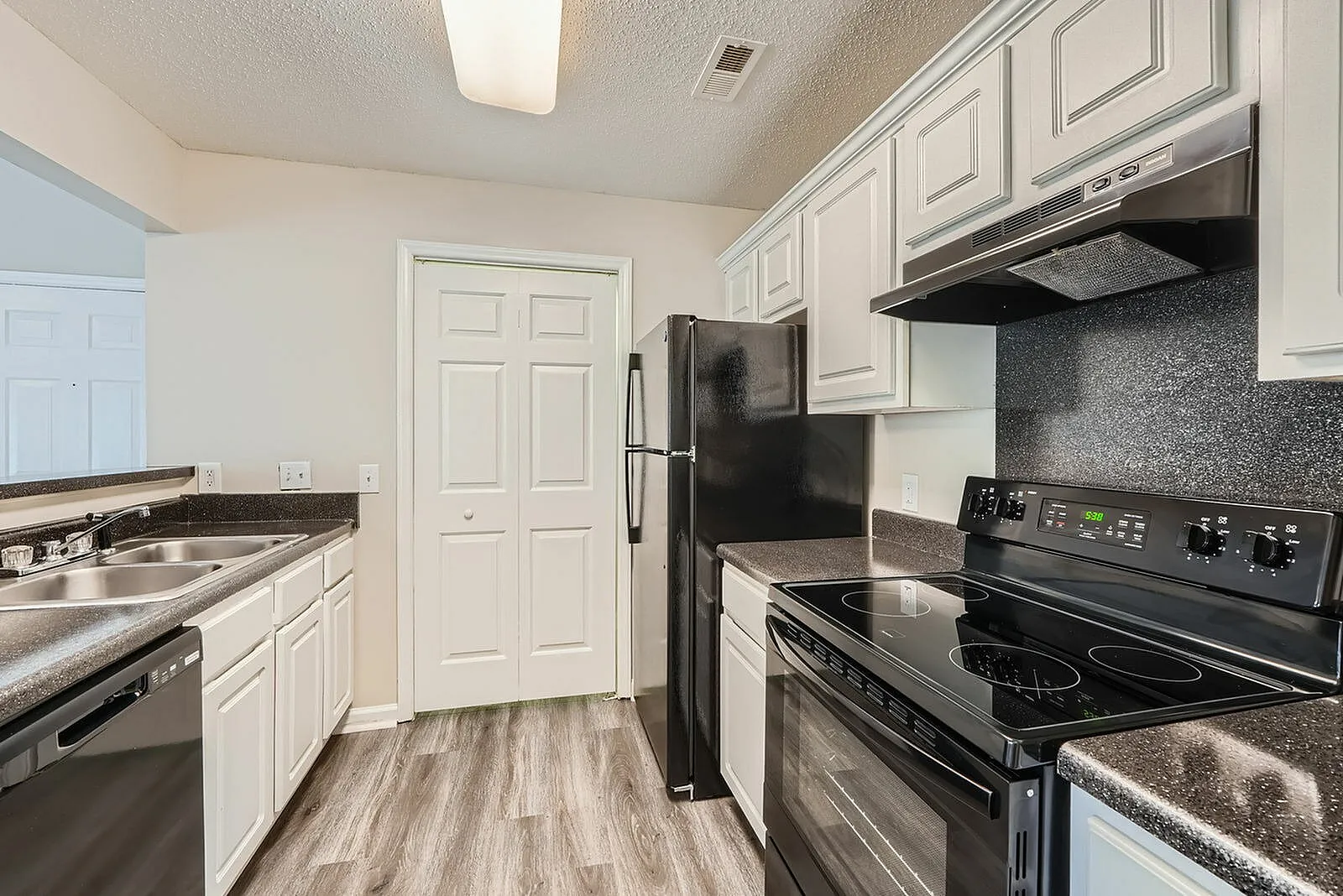 Kitchen, white shaker cabinetry, black appliances, speckled backsplash, wood-style plank flooring
