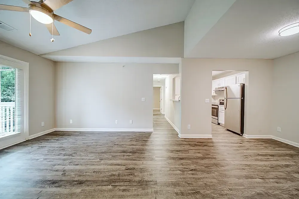 Living room with wood-style plank flooring, ceiling fan, glass door, open kitchen
