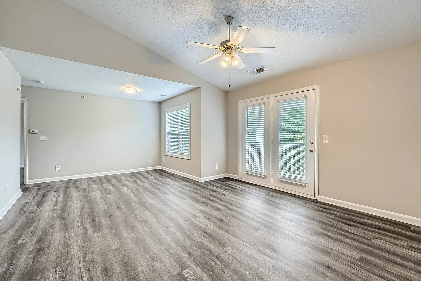 Primary bedroom, wood-style plank flooring, ceiling fan with light, glass doors to patio