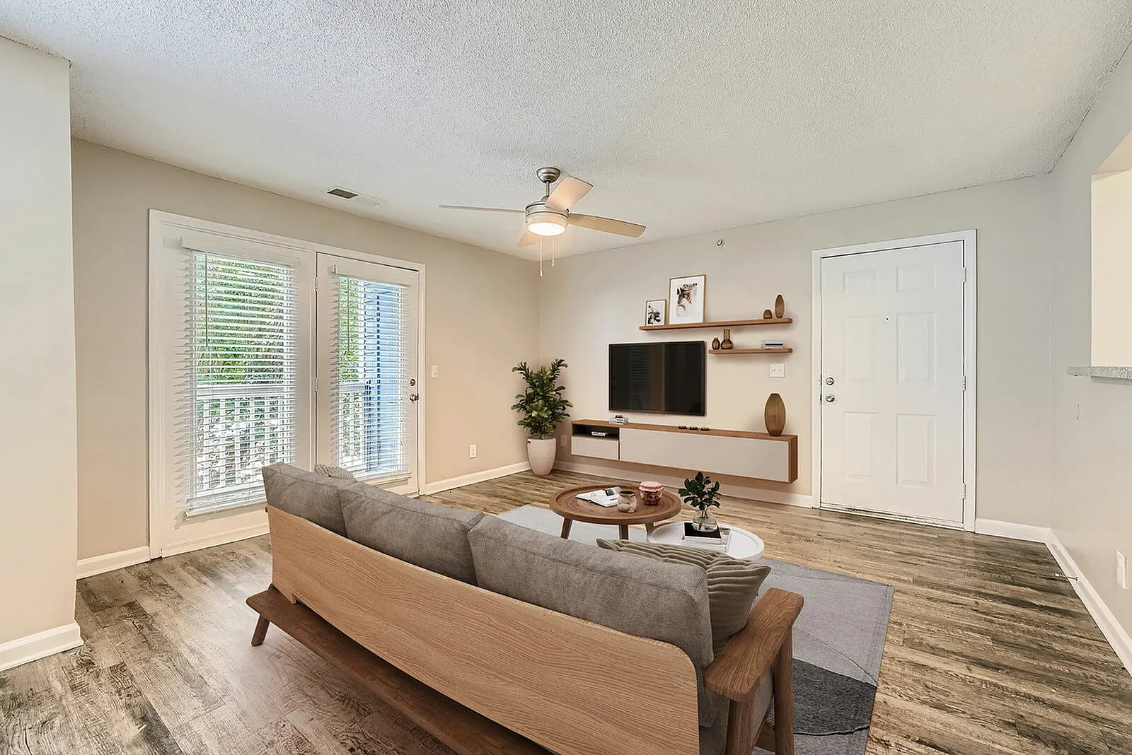 Living room, wood-style plank flooring, gray sofa, ceiling fan, TV media wall