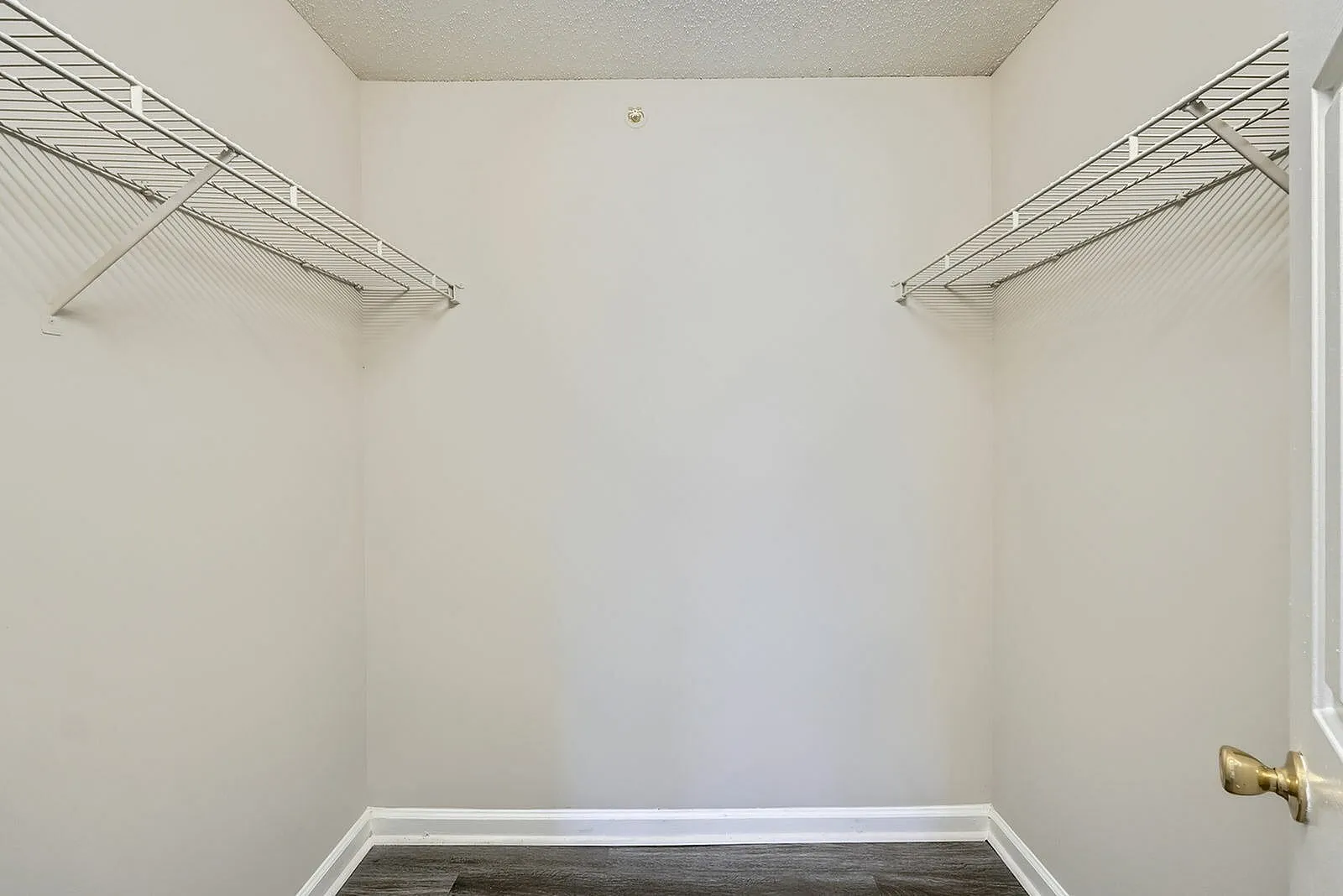 Walk-in closet with wire shelving, wood-style plank flooring, white walls