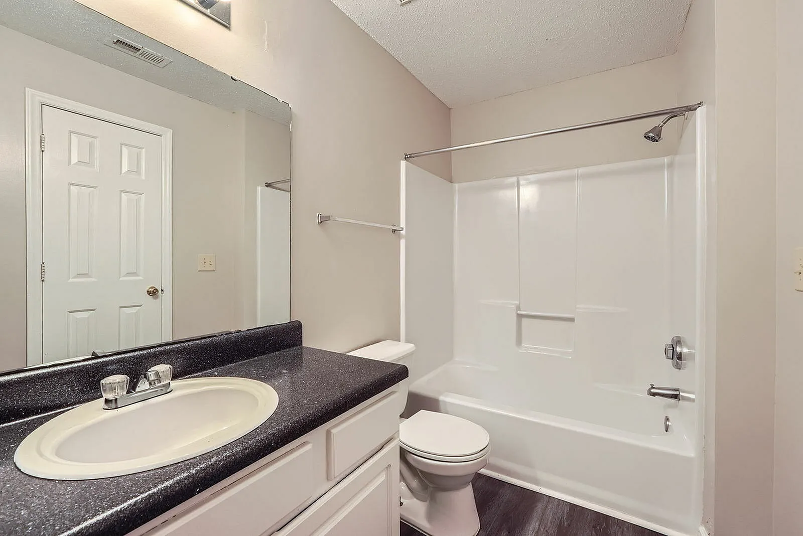 Primary bathroom, black quartz countertop, round white sink, tile shower enclosure