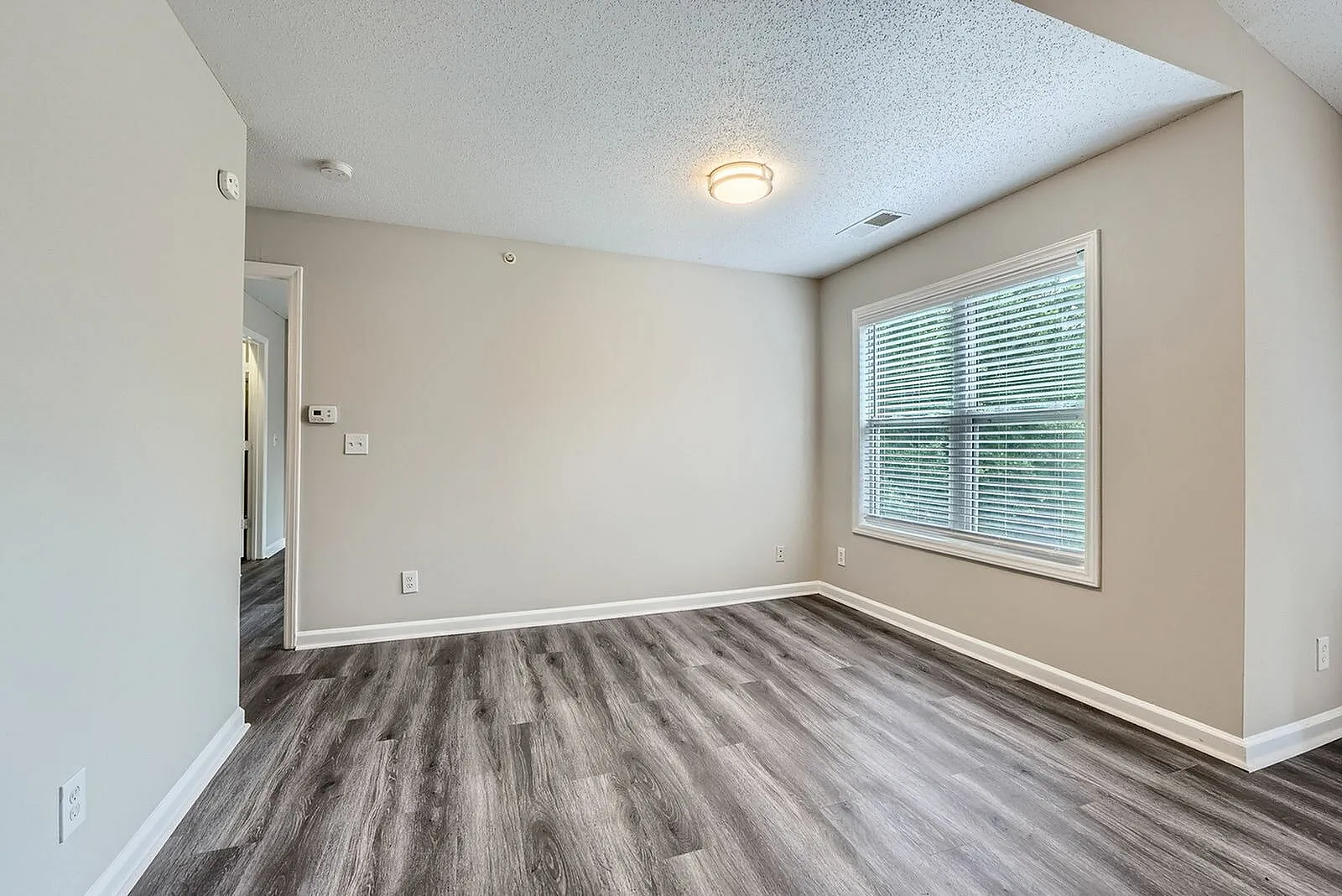 Bedroom, wood-style plank flooring, large window with shutters, recessed lighting