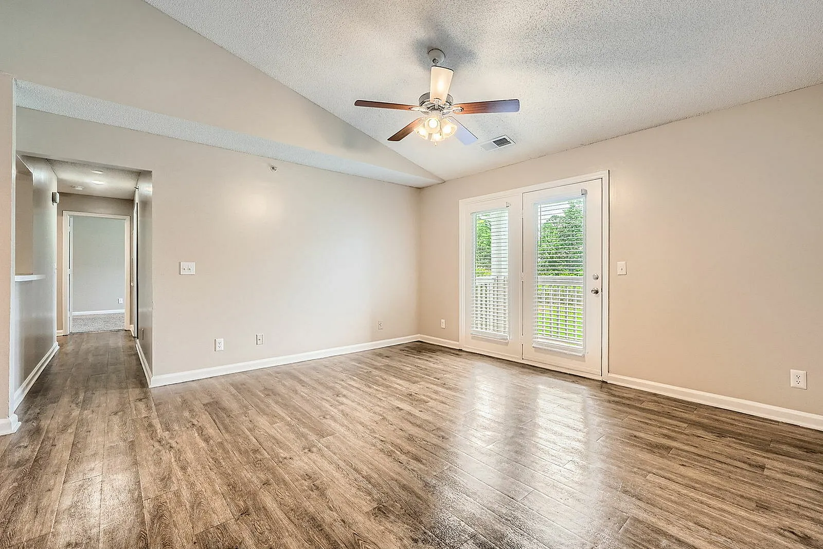 Primary bedroom, wood-style plank flooring, ceiling fan with light, glass doors with blinds