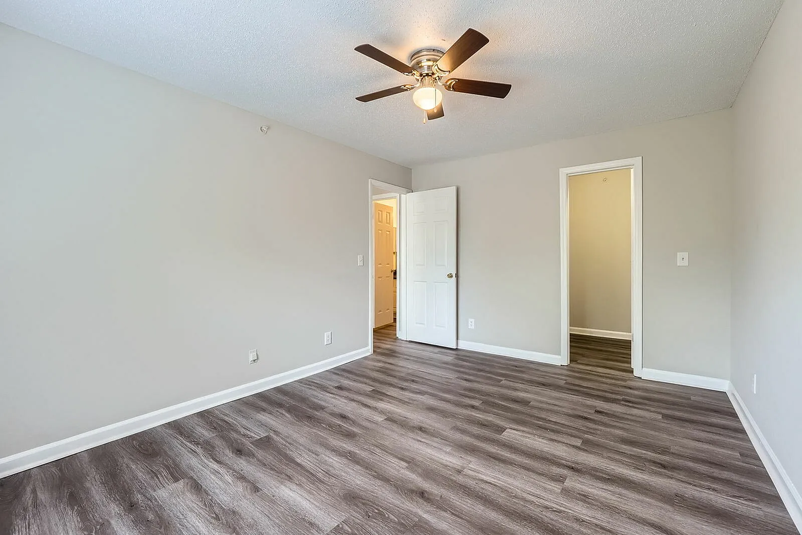 Primary bedroom, wood-style plank flooring, ceiling fan with light, dual closets