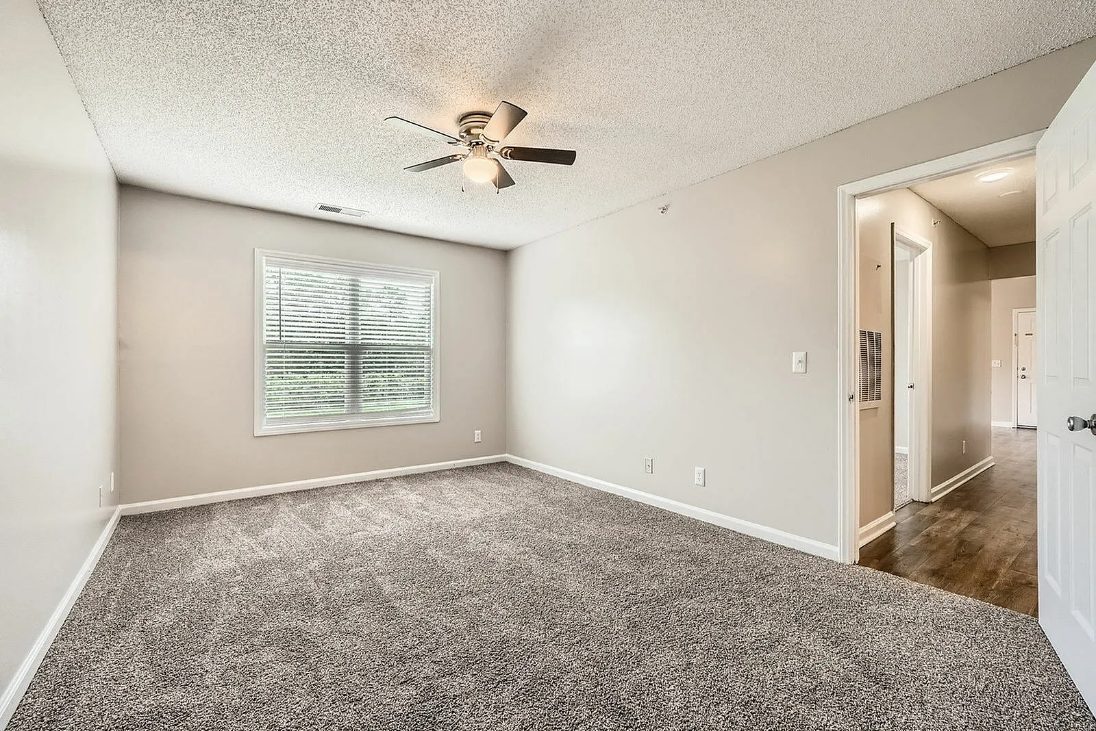 Bedroom, gray carpet flooring, ceiling fan with light fixture, window with blinds