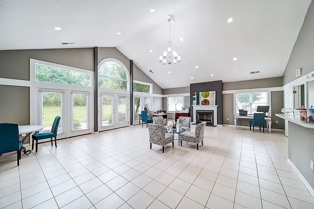Community room, white tile flooring, large windows, contemporary chandelier, fireplace