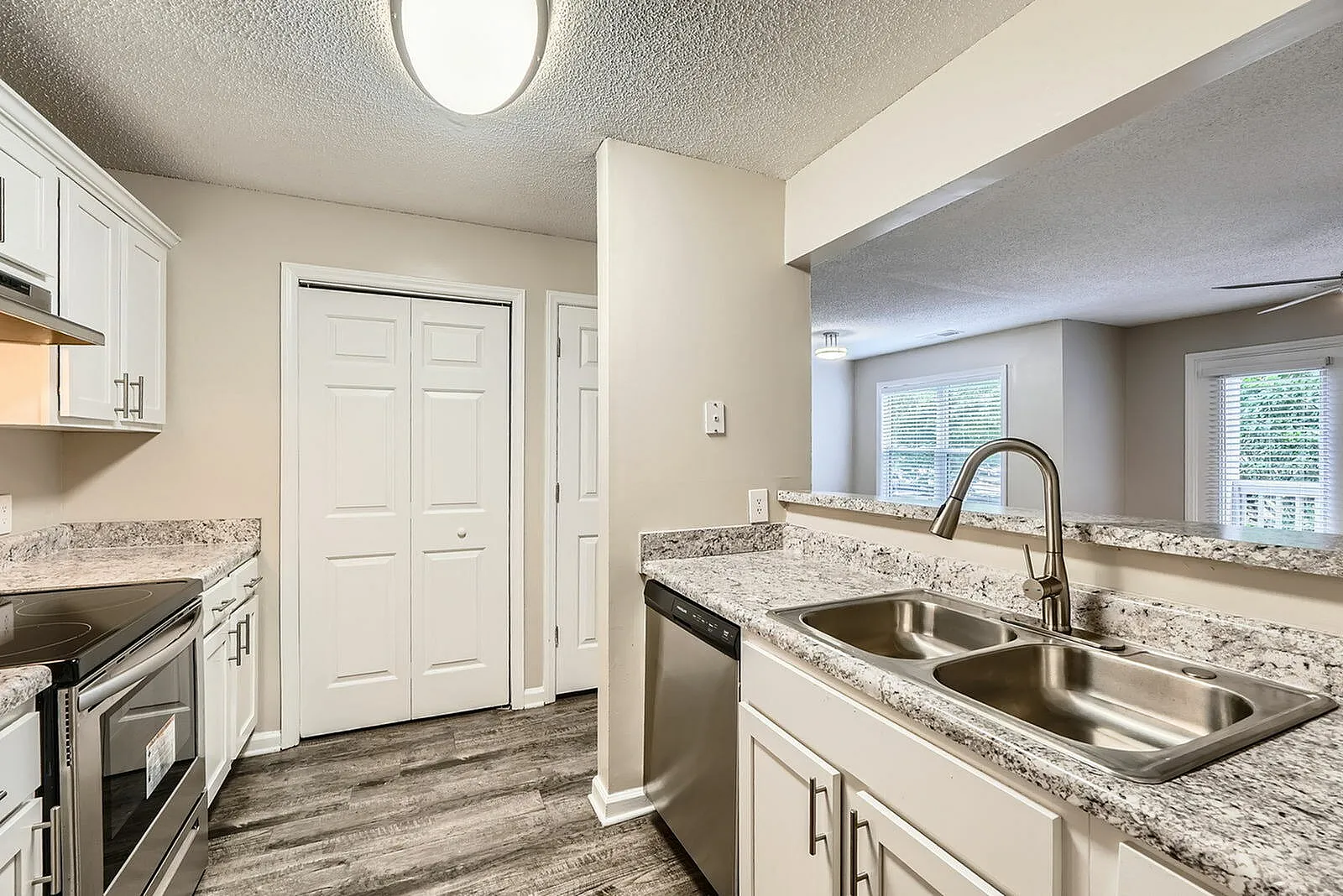 Kitchen, white shaker cabinetry, granite countertops, stainless steel sink, wood-style plank flooring