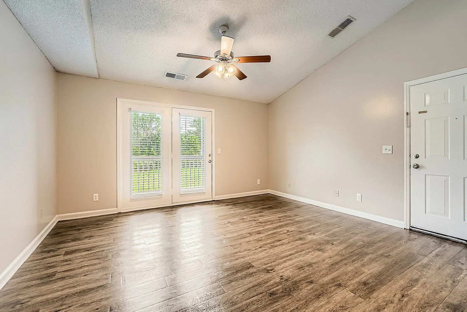 Living room with wood-style plank flooring, ceiling fan, glass doors, beige walls