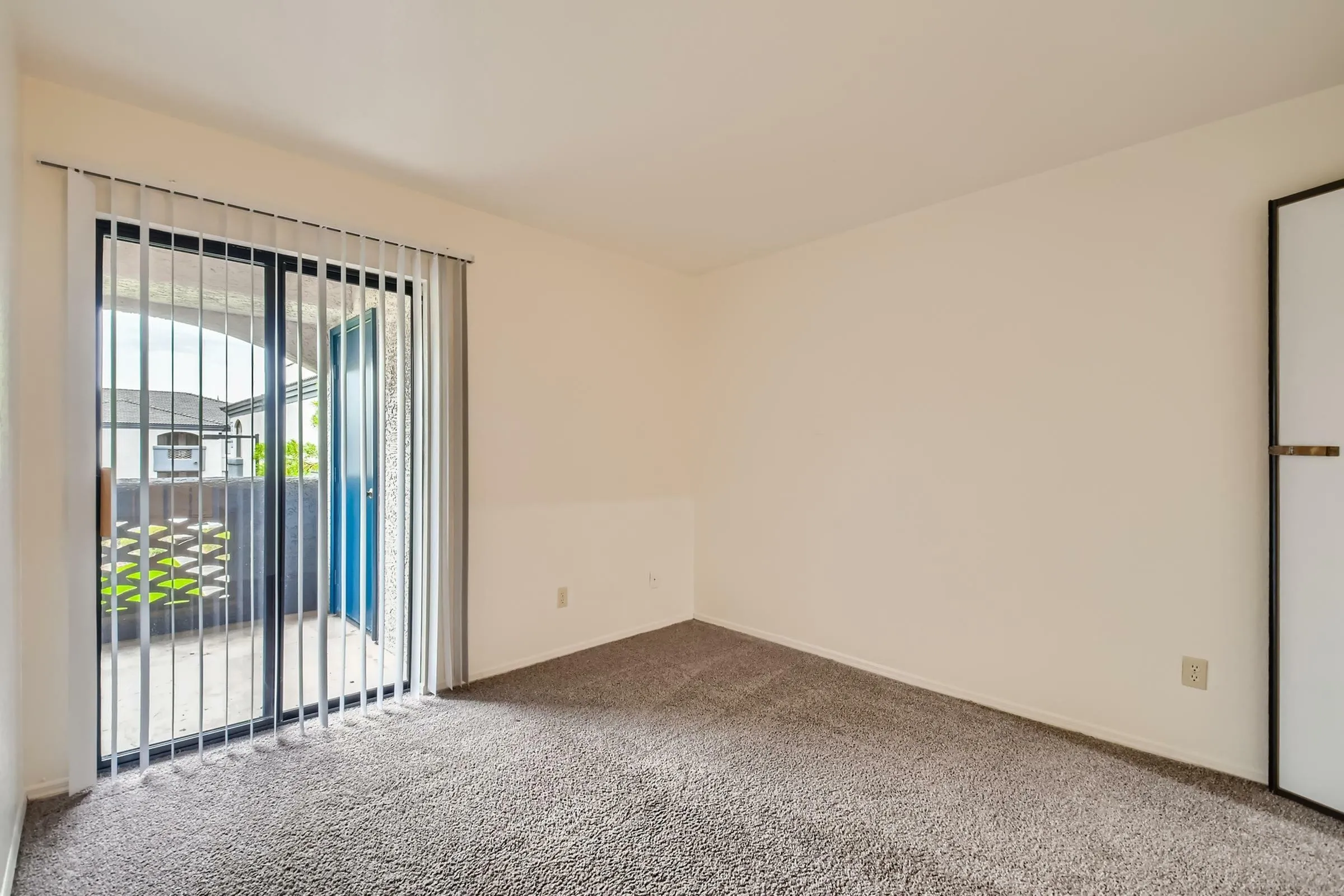 Primary bedroom, sliding glass door with vertical blinds, patio access, carpet flooring