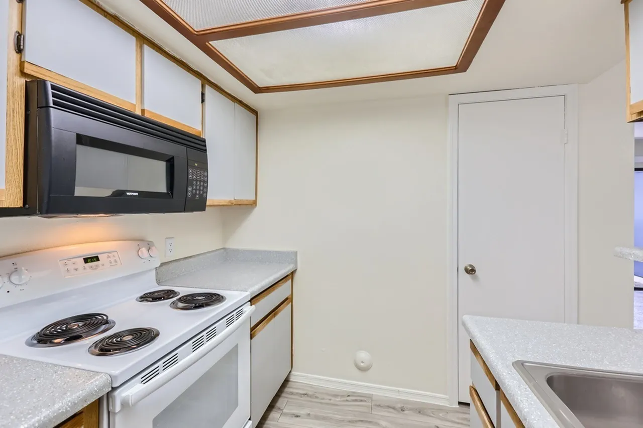 Electric coil range, over-range microwave, speckled countertop, wood-tone trim