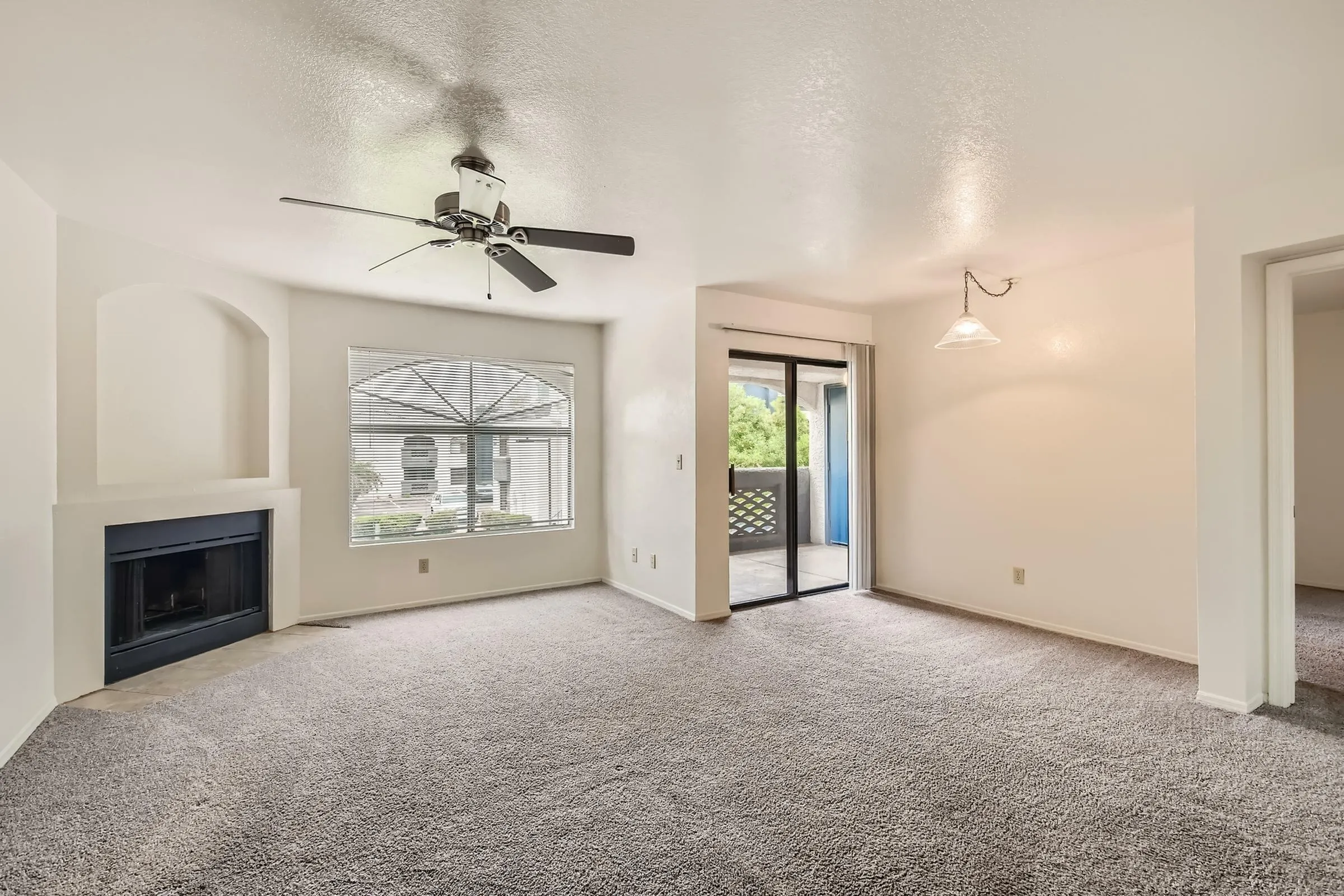 B1 Classic living room, ceiling fan, arched window, fireplace, carpet flooring, sliding glass door