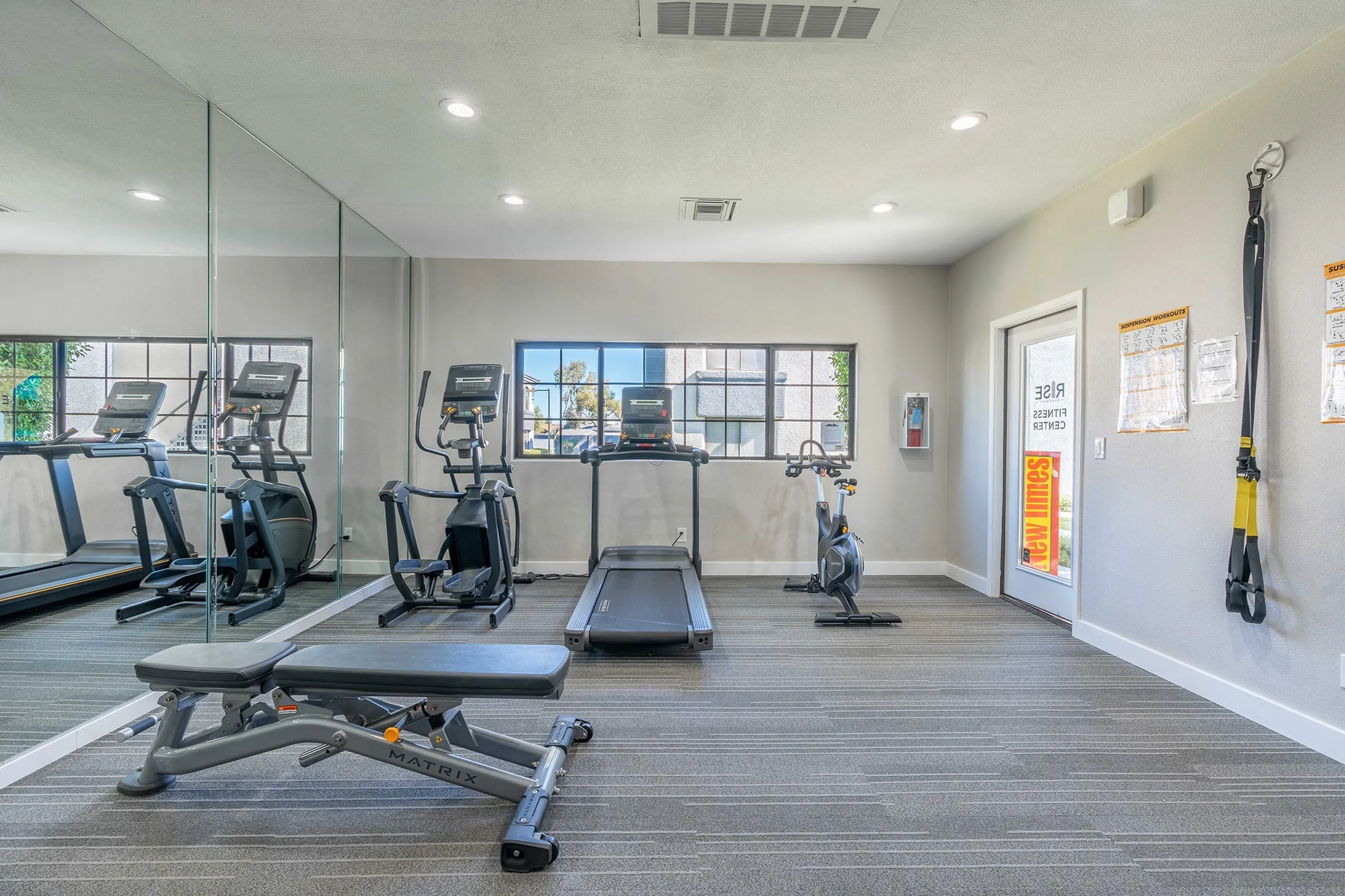 Fitness center, treadmills, elliptical, stationary bike, wood-style plank flooring, mirrored wall