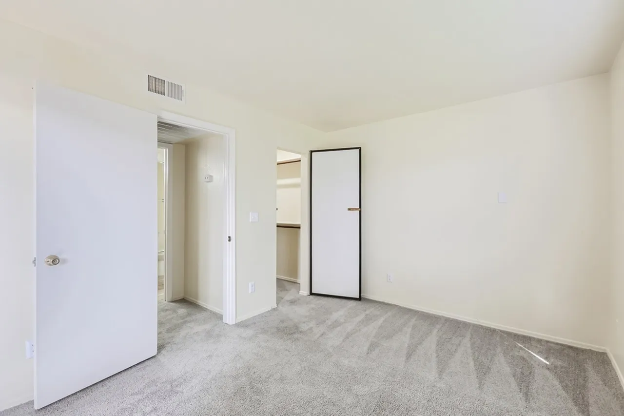 Bedroom, closet door, carpet flooring, hallway view