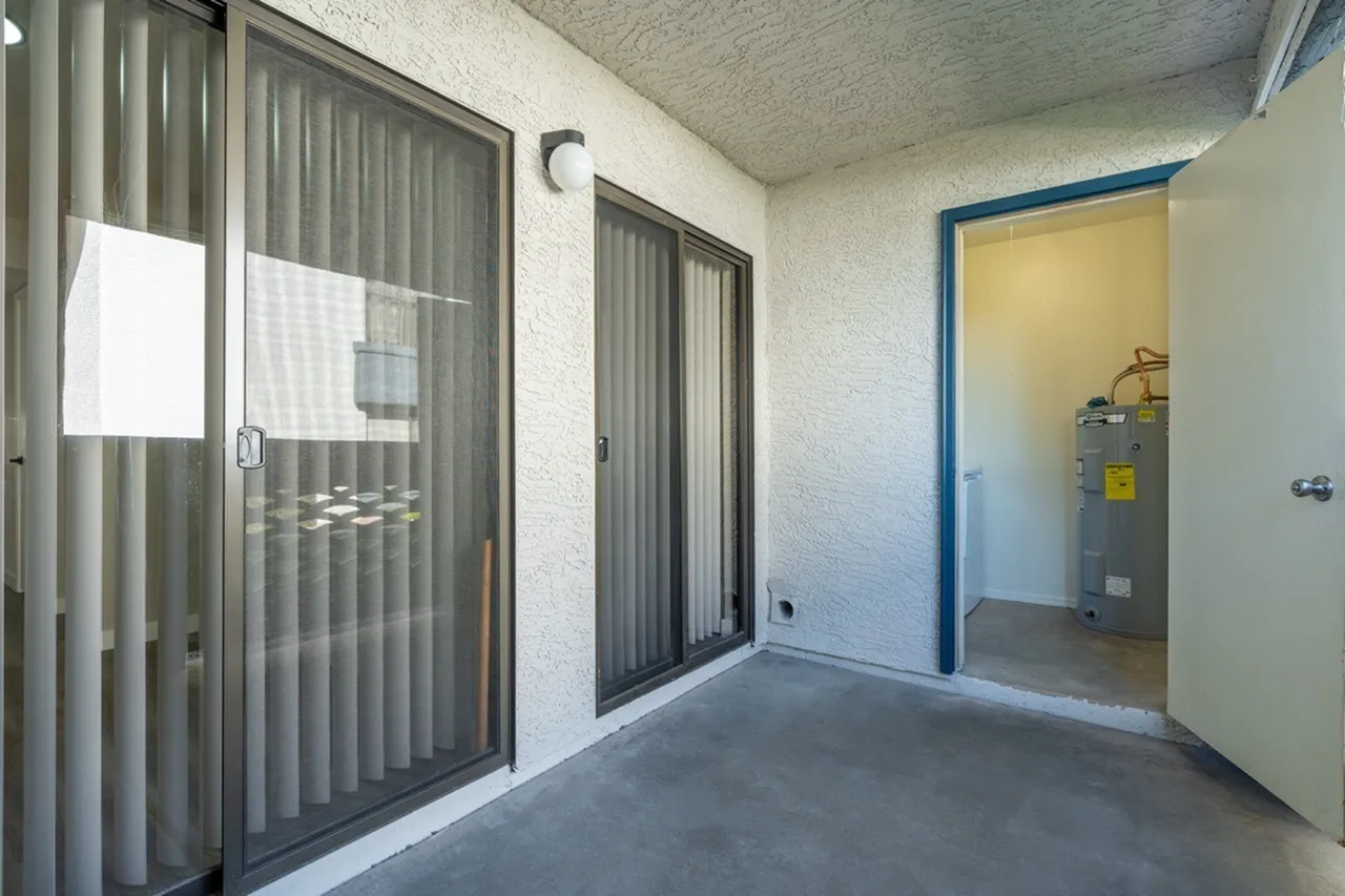 Covered patio, sliding glass doors with vertical blinds, storage closet, concrete floor