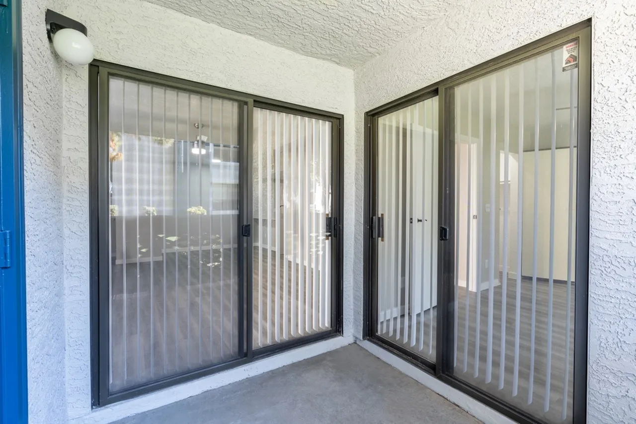 Dual sliding glass doors with vertical blinds, patio access