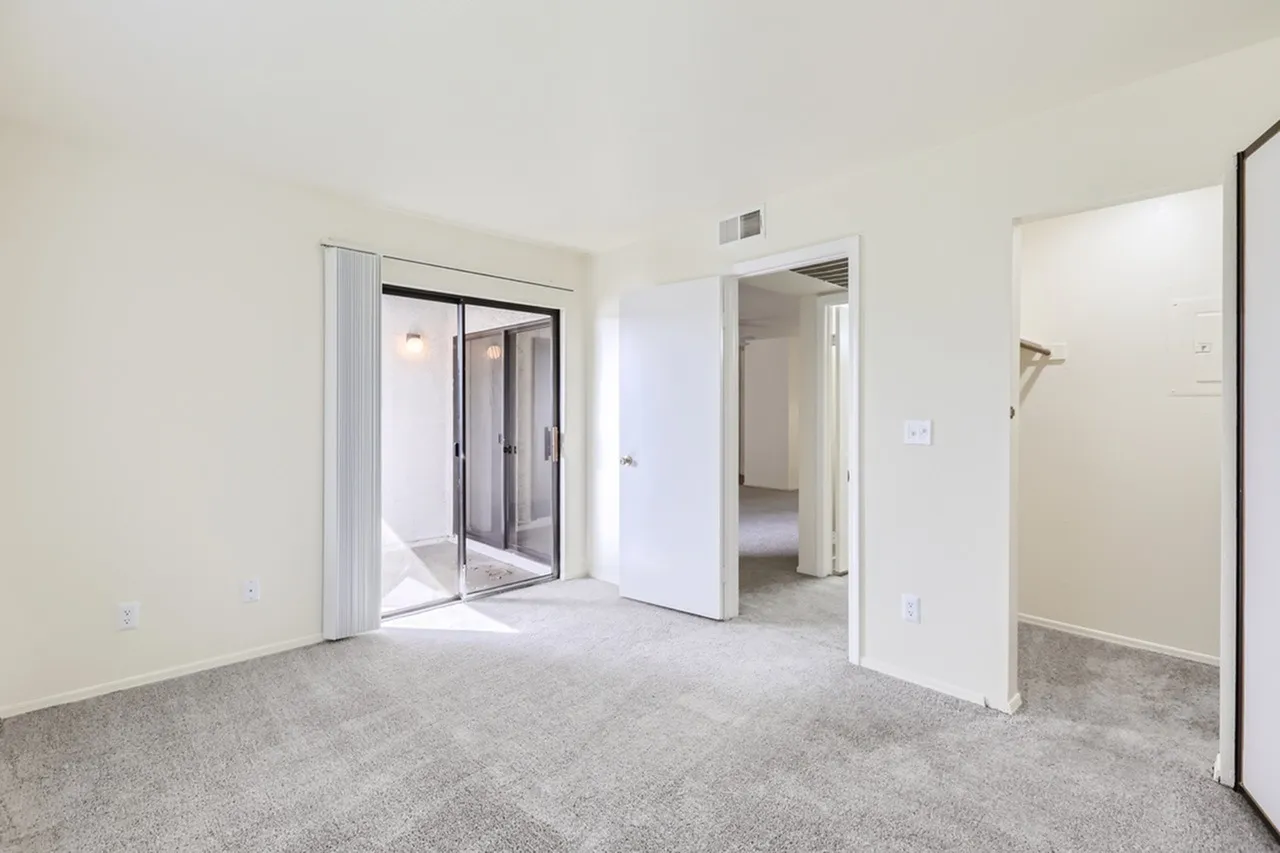 Bedroom, sliding glass door with vertical blinds, carpet flooring, doorway to hall