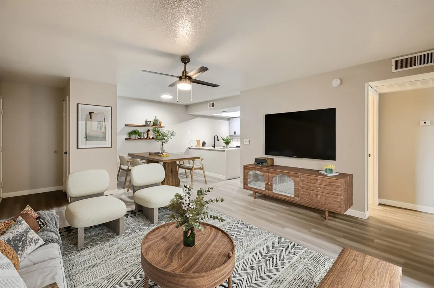 Open living and dining area, ceiling fan, wood-style plank flooring, kitchen beyond
