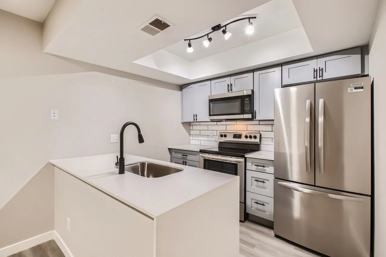 Kitchen, gray cabinetry, stainless steel appliances, white countertops, subway tile backsplash, black faucet